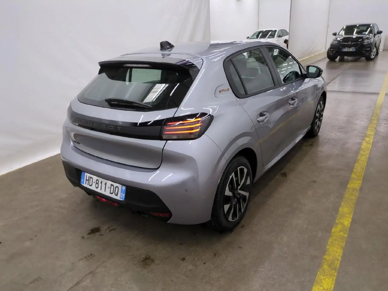 Peugeot 208 gris clair vue 3/4 arrière droit avec feux arrière LED et badge Style sur custode.