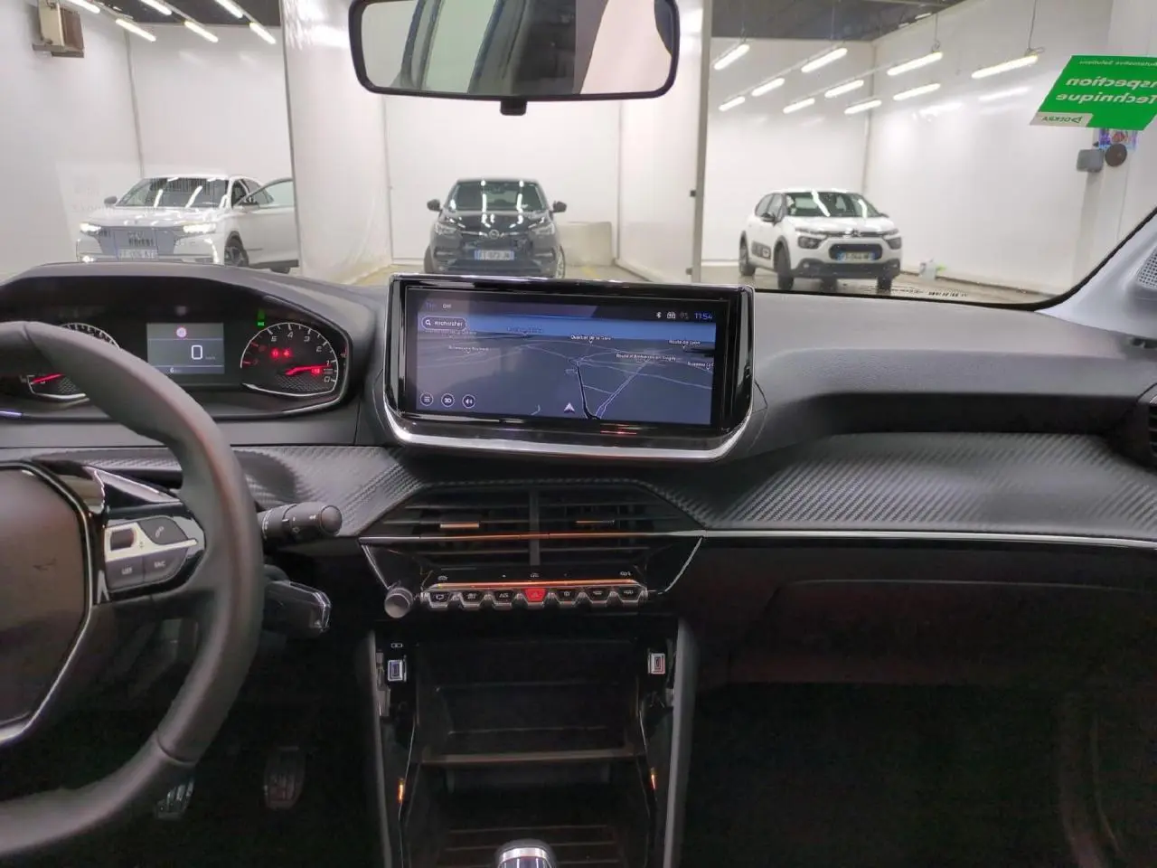 Vue intérieure avant du tableau de bord de la Peugeot 208 gris clair avec écran tactile 10 pouces et volant compact cuir.