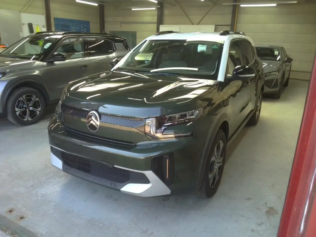 Citroën C3 Aircross 2025 vert Montana avec toit blanc, vue 3/4 avant droit dans un garage intérieur.