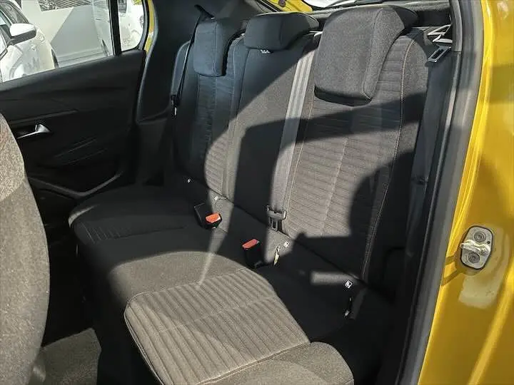 Vue intérieure côté droit montrant les sièges arrière noirs d'une Peugeot 208 jaune Faro Metal avec porte ouverte.