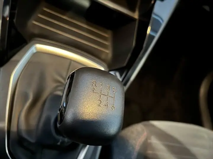 Le levier de vitesses manuel noir de la Peugeot 208 Diesel 2020, en gros plan sur l'intérieur côté conducteur.
