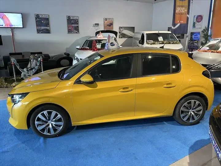 Peugeot 208 jaune Faro Metal vue de profil côté gauche dans un showroom avec d'autres véhicules en arrière-plan.