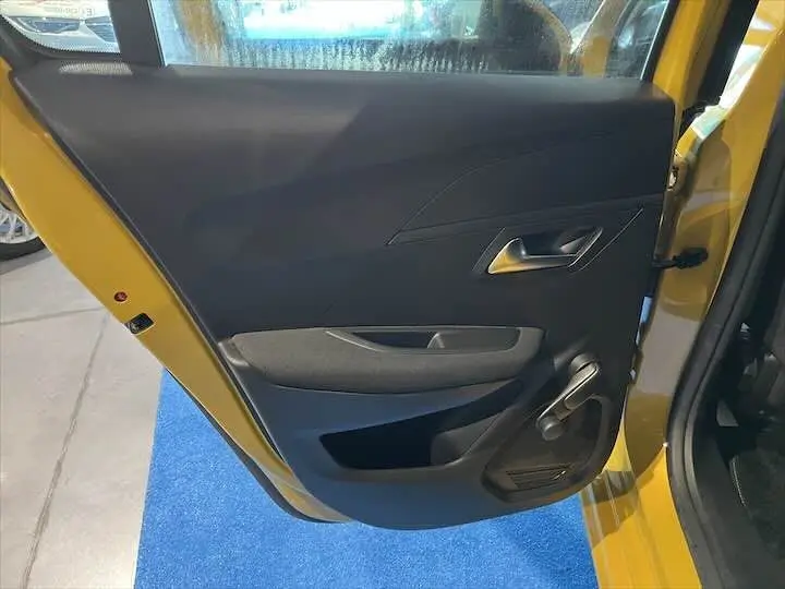 Vue rapprochée de la porte arrière droite jaune Faro métal d'une Peugeot 208 2020 avec poignée manuelle et panneau noir.