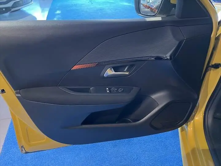 Vue intérieure côté gauche de la porte avant jaune Faro métal d'une Peugeot 208 avec garniture noire et détails modernes.