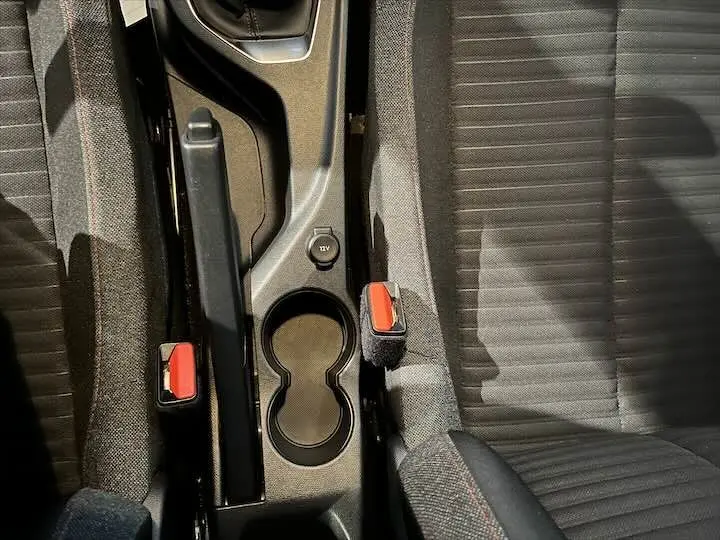 Vue plongeante sur la console centrale et les sièges avant en tissu gris foncé de la Peugeot 208 jaune Faro Metal.