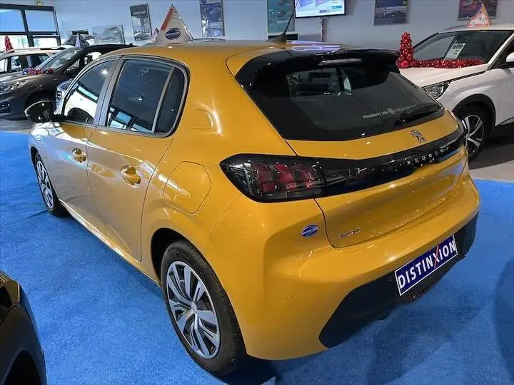 Vue 3/4 arrière droite d'une Peugeot 208 jaune Faro Metal exposée en showroom avec jantes alliage et vitres teintées.