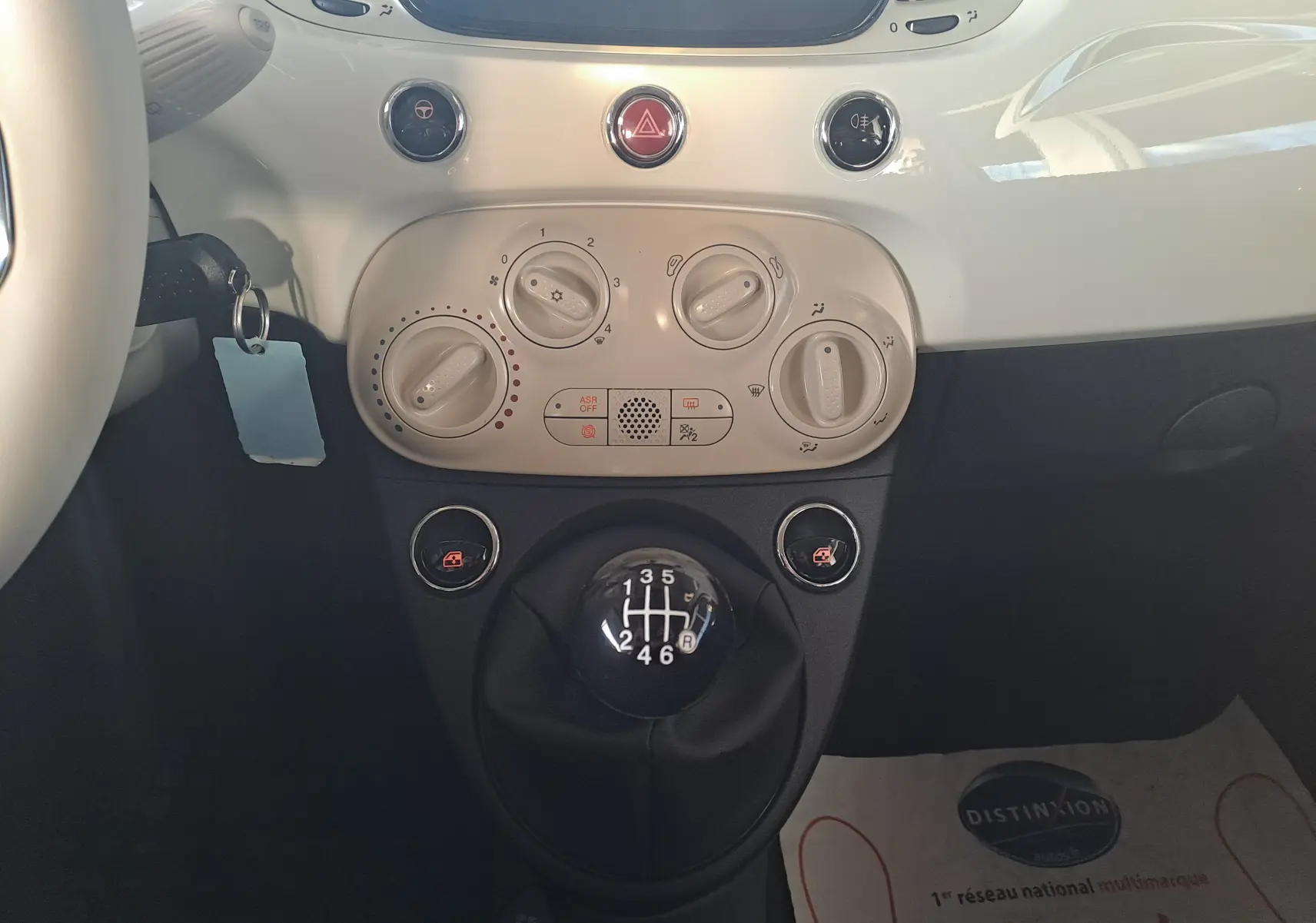 Vue rapprochée du levier de vitesses manuel et des commandes de climatisation blanches dans l'habitacle d'une FIAT 500 blanche 2023.