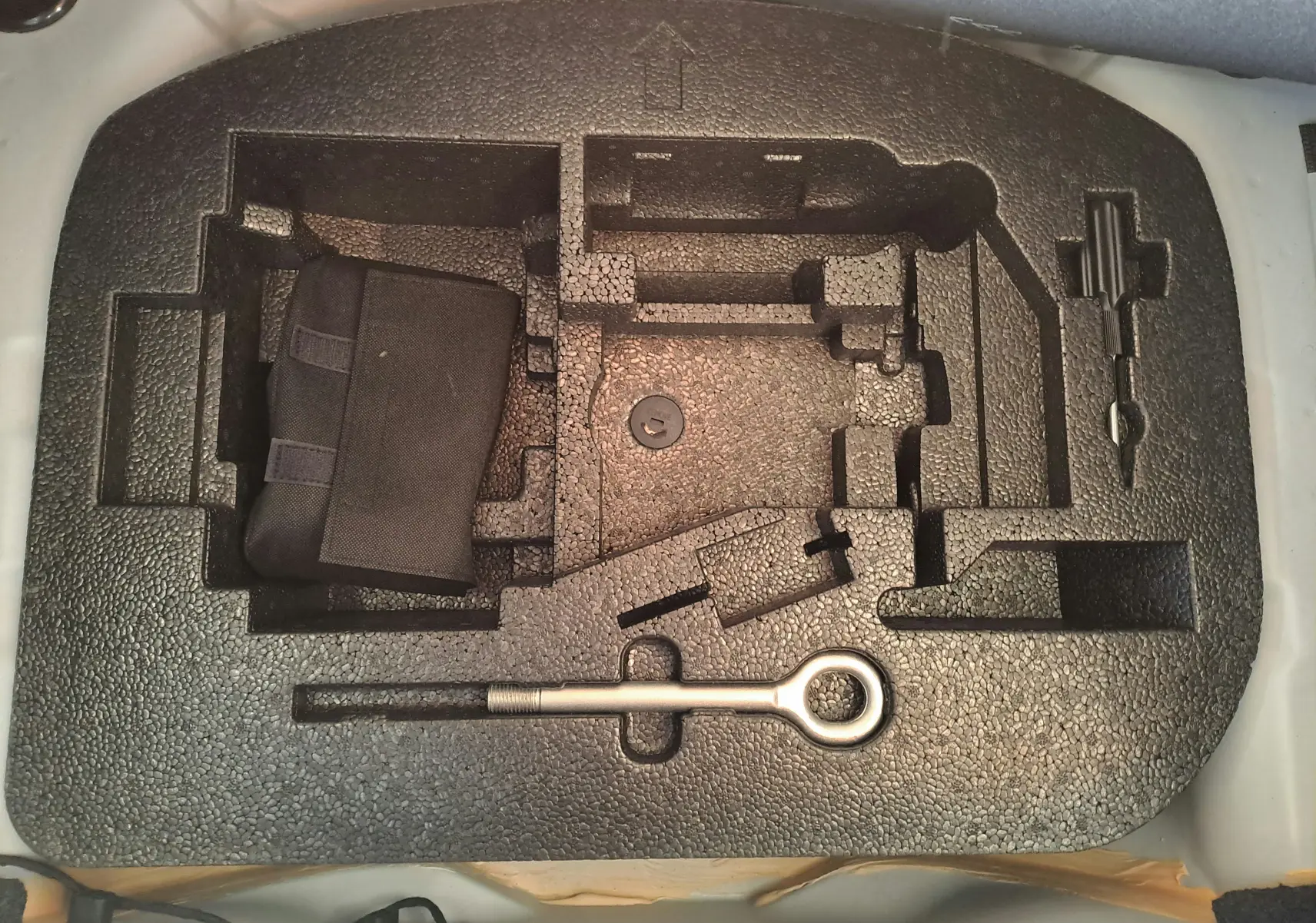 Gros plan sur le rangement en mousse noir du coffre d'une Fiat 500 blanche 2023, avec outils et pochette intégrés.