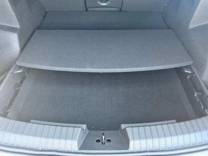 Coffre ouvert du Dacia Bigster blanc, vue plongeante sur le compartiment de rangement sous plancher.