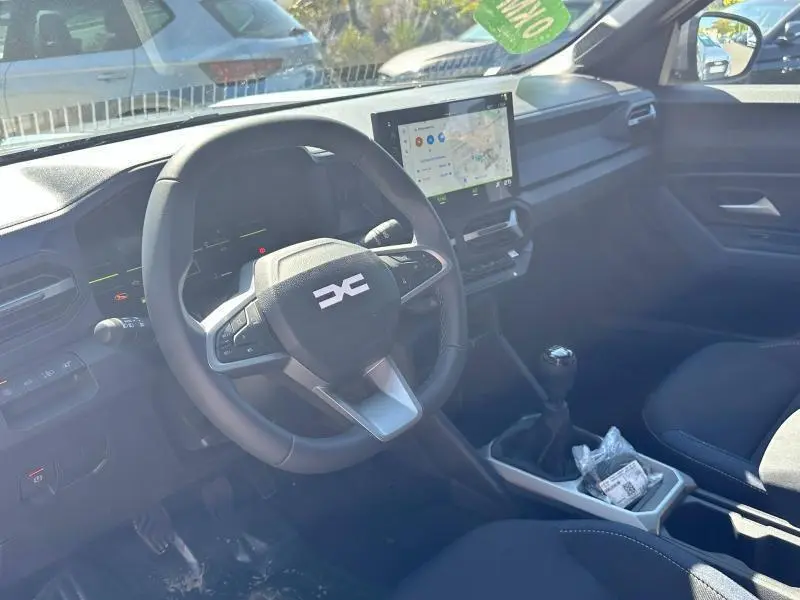 Intérieur du Dacia Bigster blanc 2025 vu côté conducteur, volant multifonction et écran tactile central visibles.