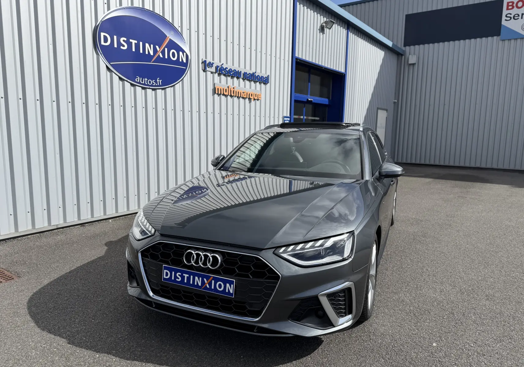 Audi A4 Avant gris Daytona métal vue 3/4 avant droit, avec calandre hexagonale et phares LED distinctifs.