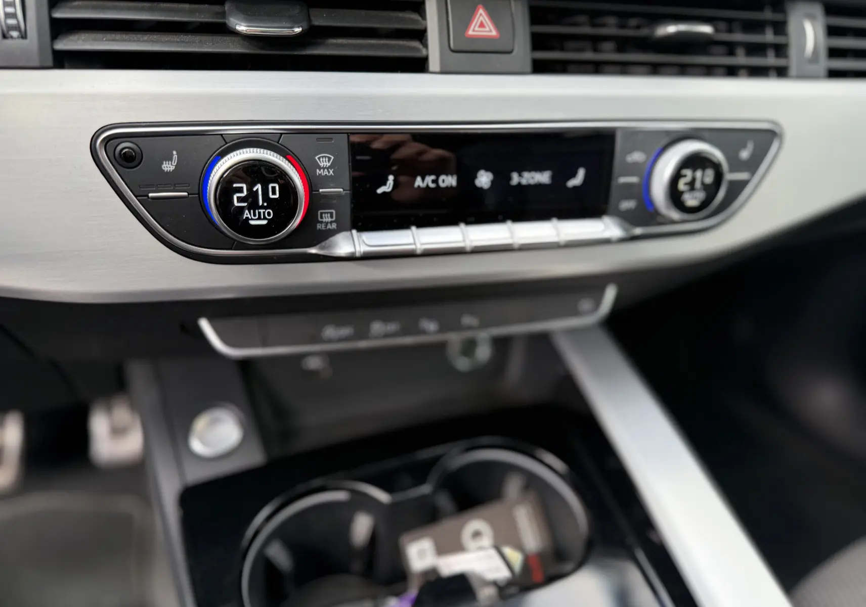 Gros plan sur la console centrale de l'Audi A4 Avant 35 TDI 2023, affichant la climatisation digitale à 21°C.
