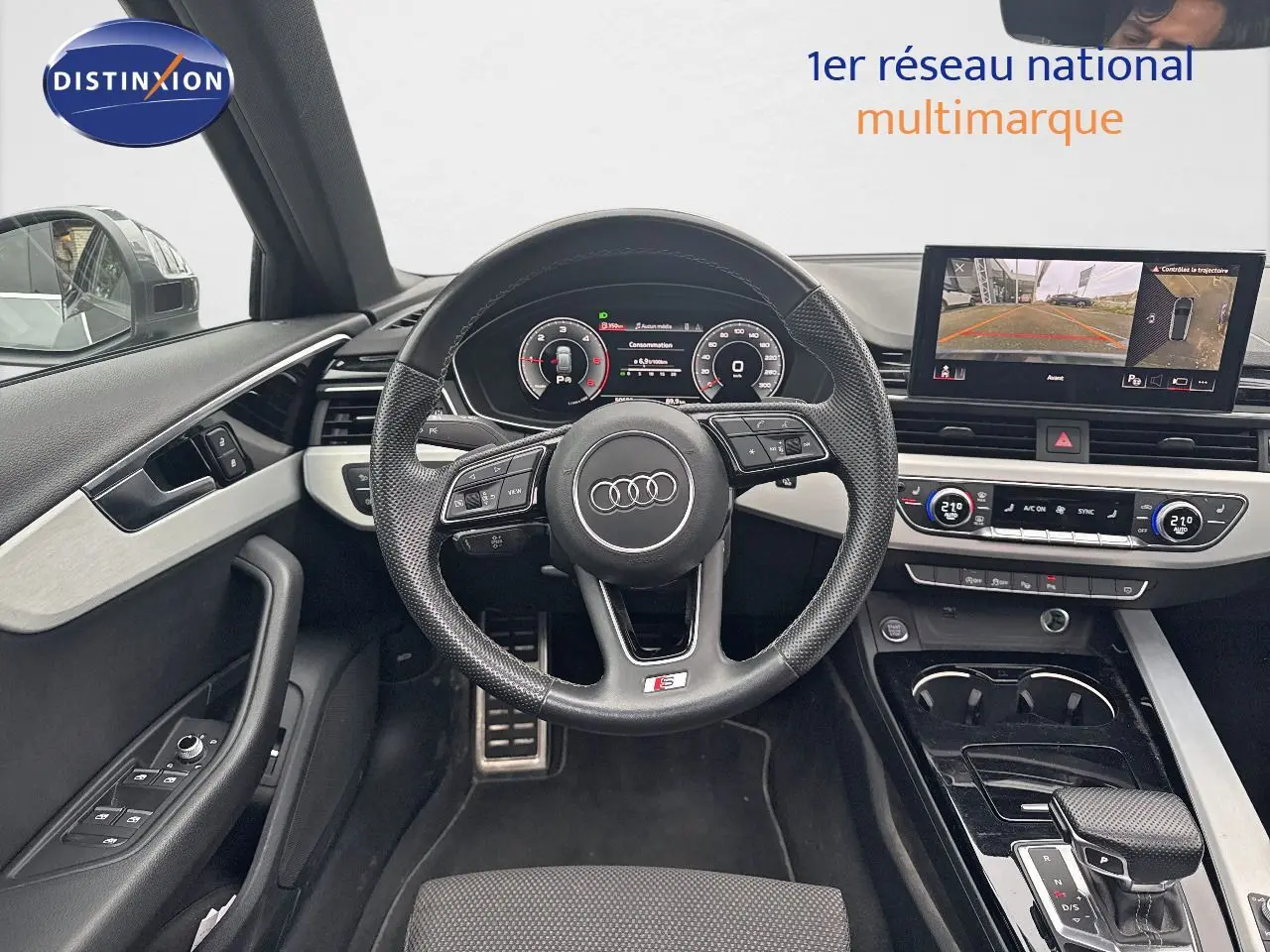 Intérieur de l'Audi A4 Avant 35 TDI 2023, vue du poste de conduite avec volant S-Line et écran multimédia allumé.