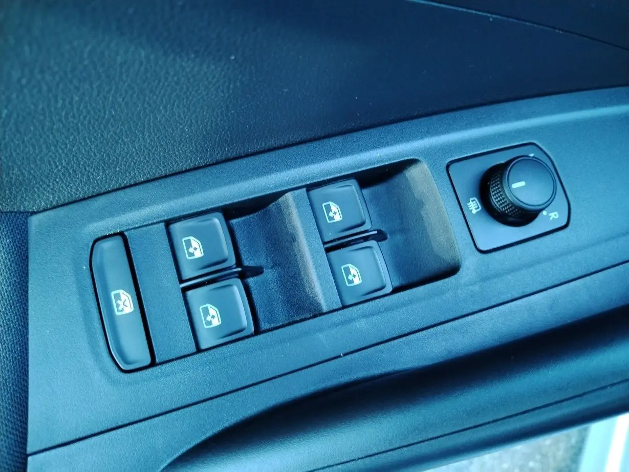 Gros plan sur les commandes des vitres électriques et réglage des rétroviseurs côté conducteur d'une Skoda Fabia blanche 2023.
