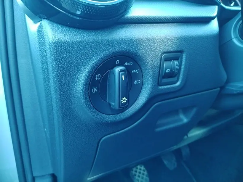 Gros plan sur le tableau de bord noir de la Skoda Fabia 2023 montrant la molette de réglage des phares et l’intensité lumineuse.