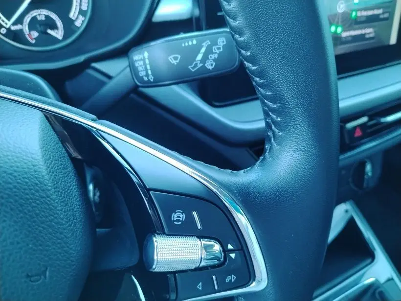 Gros plan sur le volant en cuir noir de la Skoda Fabia 2023, avec commandes intégrées et tableau de bord partiellement visible.