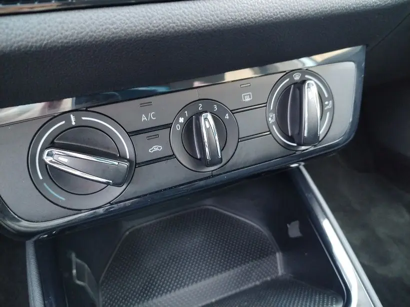 Vue rapprochée des commandes de climatisation noires de la Skoda Fabia 2023, avec réglages manuels et finition brillante.