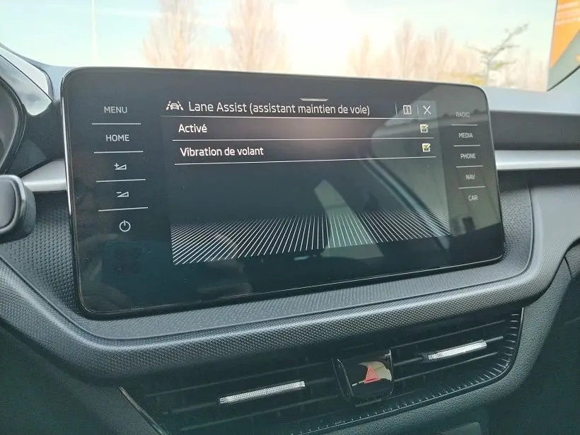 Écran tactile central de la Skoda Fabia 2023 affichant l'activation de l'assistant maintien de voie, intérieur noir.