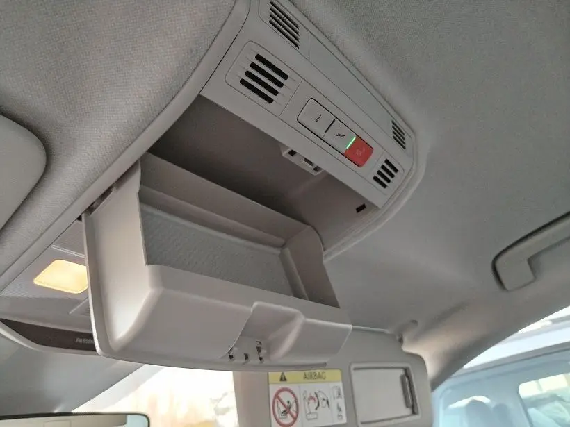 Vue intérieure en plongée sur le rangement de plafond ouvert de la Skoda Fabia blanche 2023, avec éclairage et commandes intégrées.