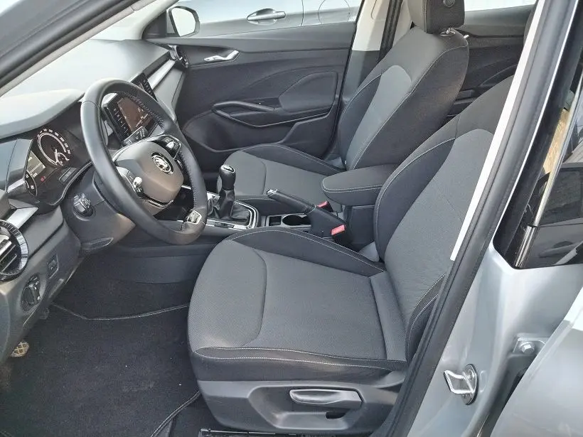 Vue intérieure côté conducteur de la Skoda Fabia blanche 2023, sièges tissu gris et boîte manuelle visible.