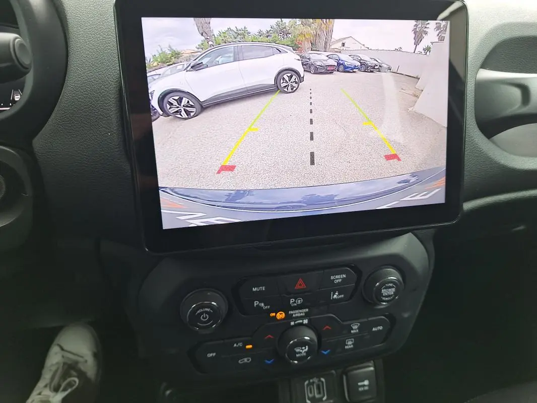 Vue intérieure centrée sur l’écran tactile affichant la caméra de recul d’une Jeep Renegade bleu 2024.