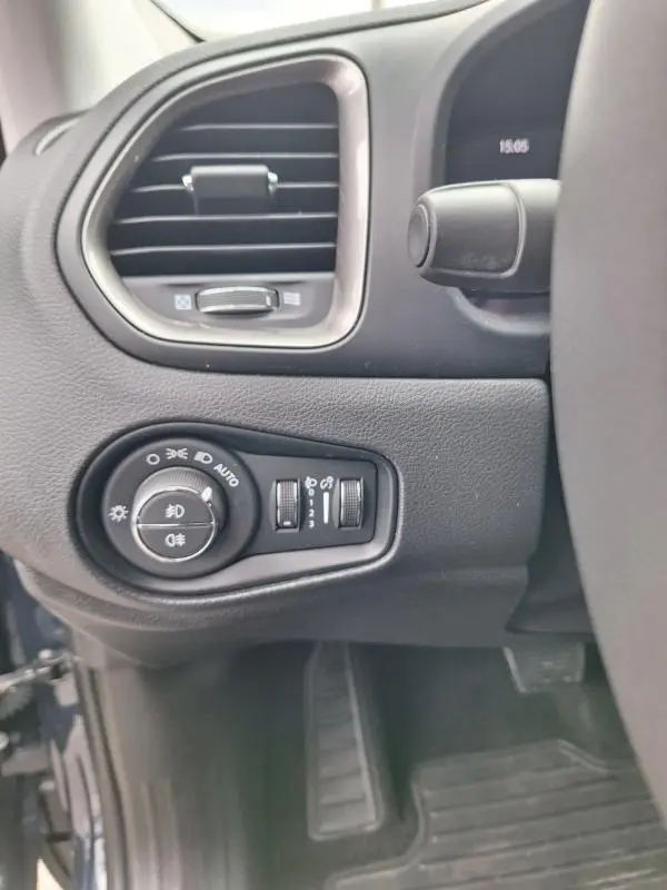 Détail intérieur côté gauche du tableau de bord bleu de la Jeep Renegade 2024 avec commandes des phares et aérateur.