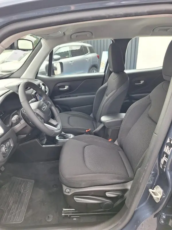 Vue intérieure côté conducteur du Jeep Renegade bleu 2024, sièges noirs avec accoudoir central et volant multifonction.