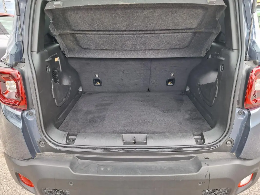 Coffre ouvert d’un Jeep Renegade bleu 2024, vue arrière montrant l’espace de chargement vide et la garniture intérieure.
