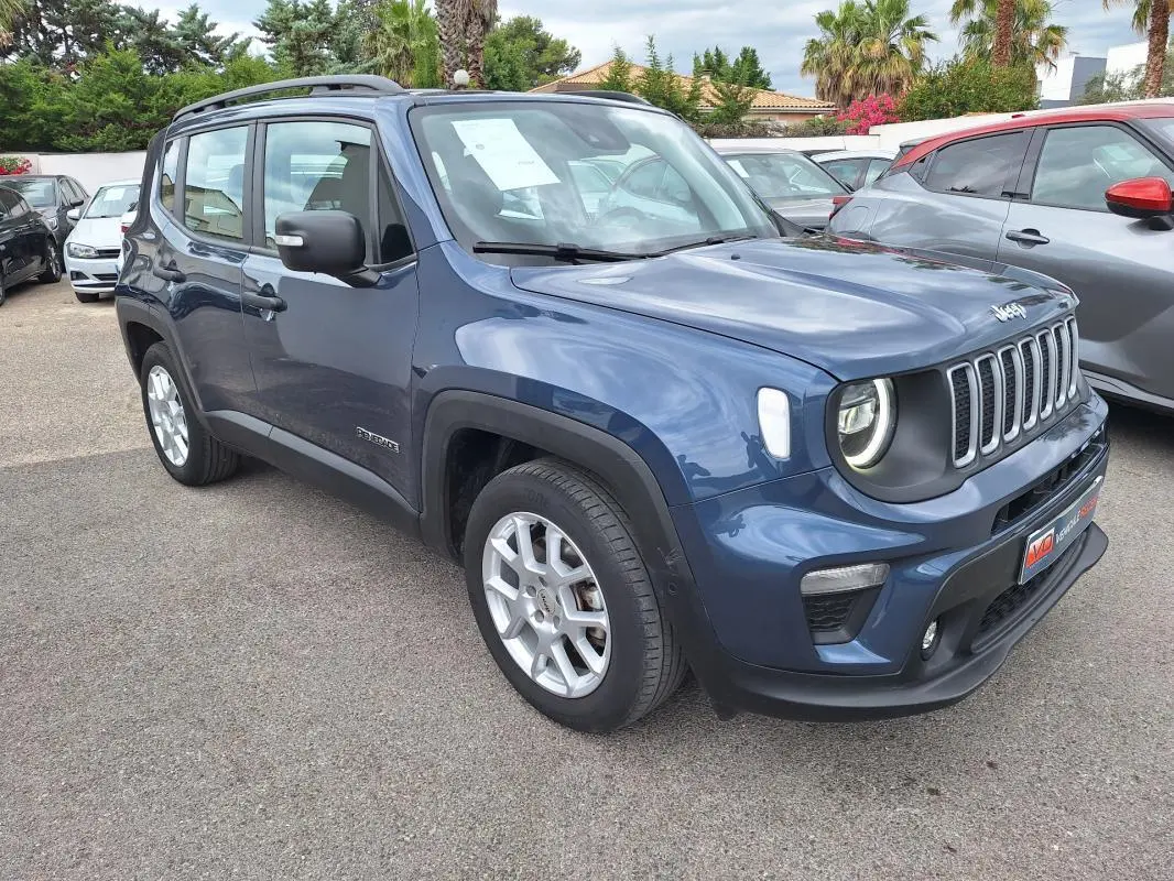 Jeep Renegade bleu en 3/4 avant droit, avec barres de toit et jantes alliage 17 pouces visibles.