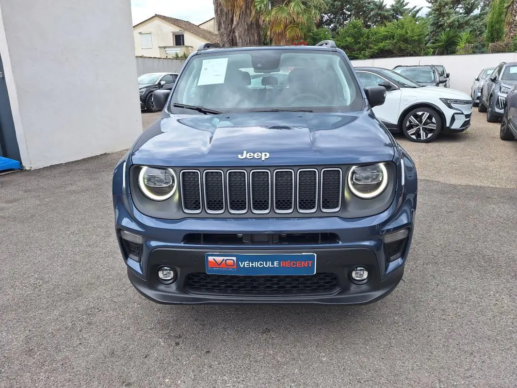 Vue avant d'un Jeep Renegade bleu 2024 avec phares ronds allumés et calandre à sept fentes distinctives.