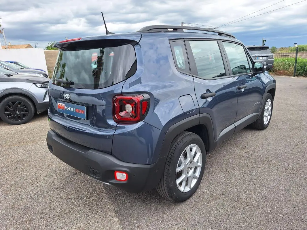 Jeep Renegade bleu vue 3/4 arrière droit, avec barres de toit et jantes alliage 17 pouces visibles.