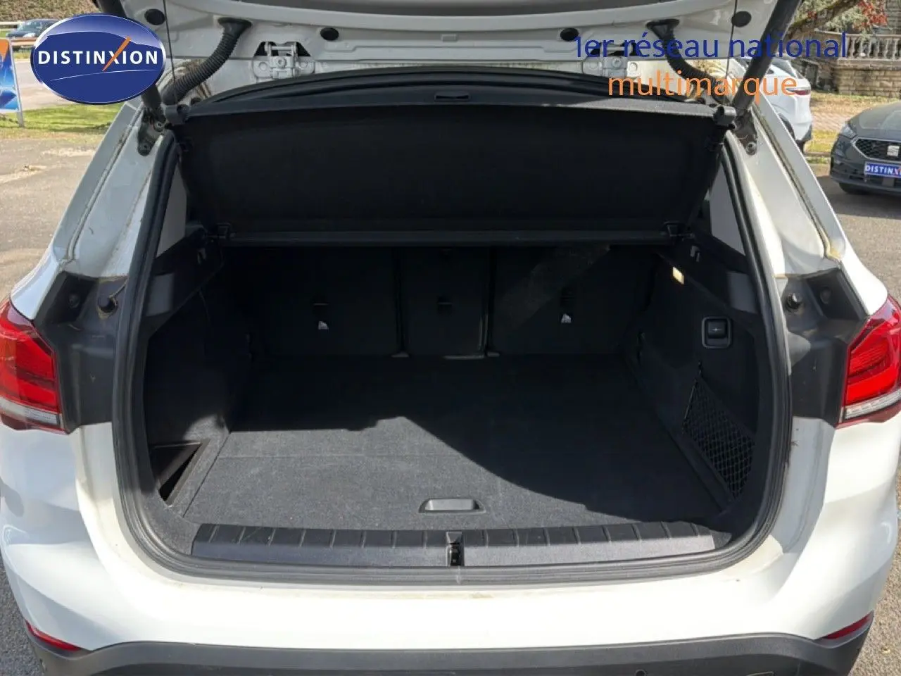 Coffre ouvert d'un BMW X1 blanc 2022 vu de l'arrière, montrant un espace de chargement spacieux et propre.