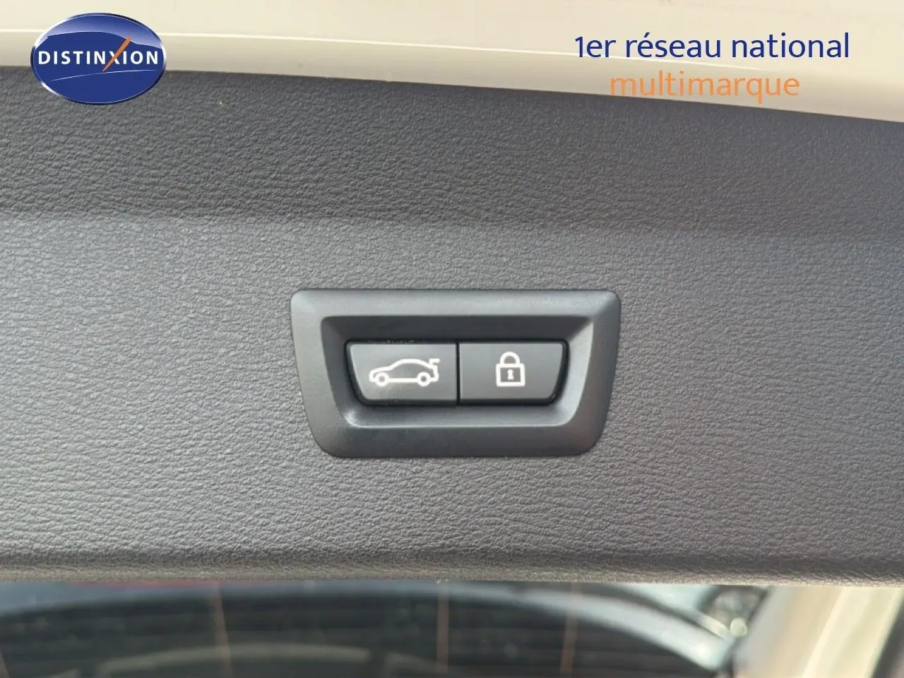 Boutons d'ouverture et de verrouillage de hayon sur la garniture intérieure blanche d'un BMW X1 2022 vue en gros plan.