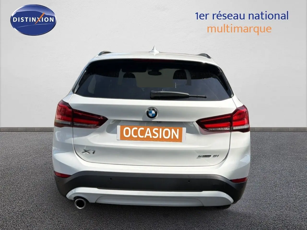 Vue arrière d’un BMW X1 blanc de 2022 avec feux rouges et plaque « OCCASION » visible sur un fond neutre.