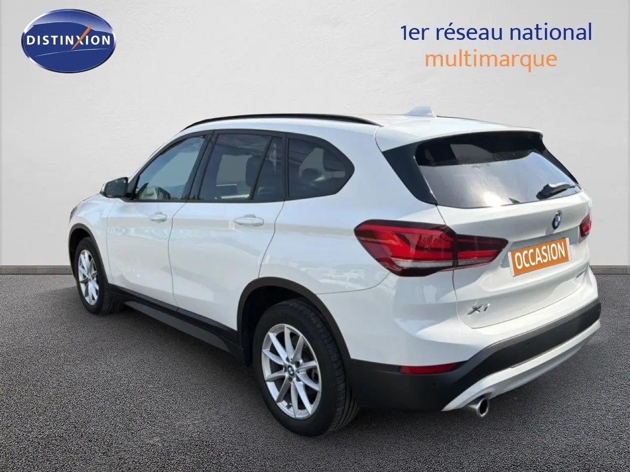 BMW X1 blanc vu en 3/4 arrière droit, mettant en valeur ses feux arrière et sa silhouette compacte SUV.