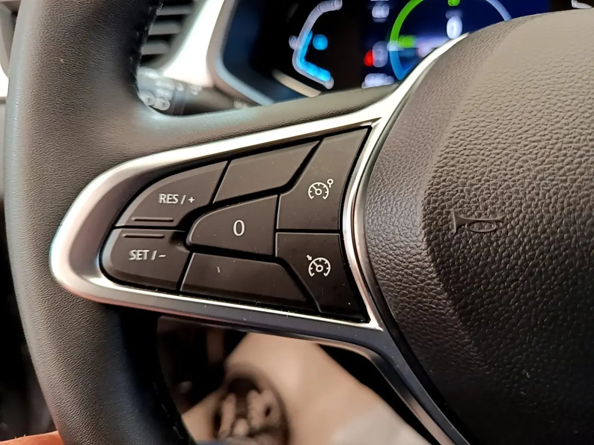 Gros plan sur les commandes du régulateur de vitesse au volant cuir du Renault Captur Zen E-Tech hybride 2022.
