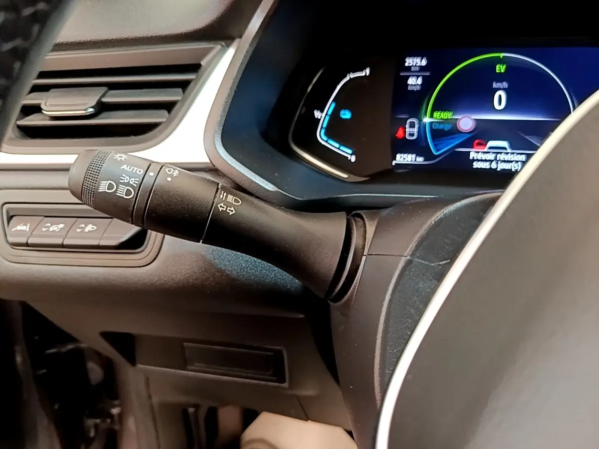 Gros plan sur la commande des phares et clignotants à gauche du volant du Renault Captur gris foncé, tableau de bord numérique visible.