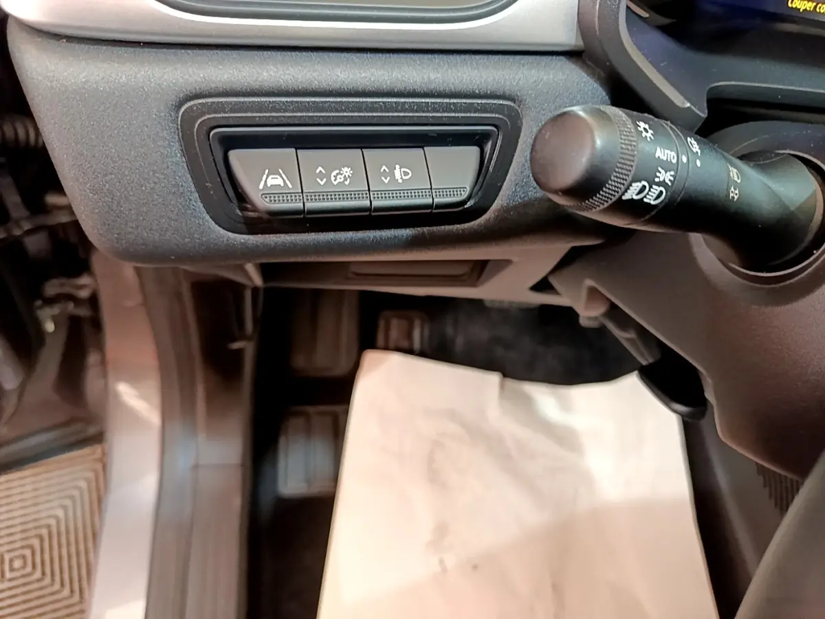 Détail du tableau de bord côté gauche du Renault Captur gris foncé, avec commandes d'assistance et commande de phares.