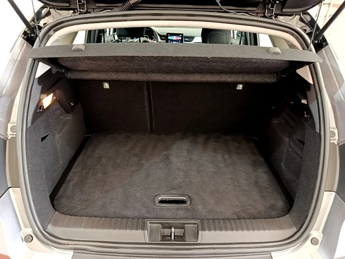 Coffre ouvert vu de l'arrière d'un Renault Captur Zen E-Tech hybride gris foncé, intérieur noir et tablette de coffre visible.