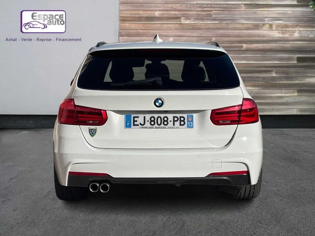 Vue arrière d'une BMW Série 3 Touring F31 blanche, version 330DA XDrive M Sport avec double sortie d'échappement à gauche.