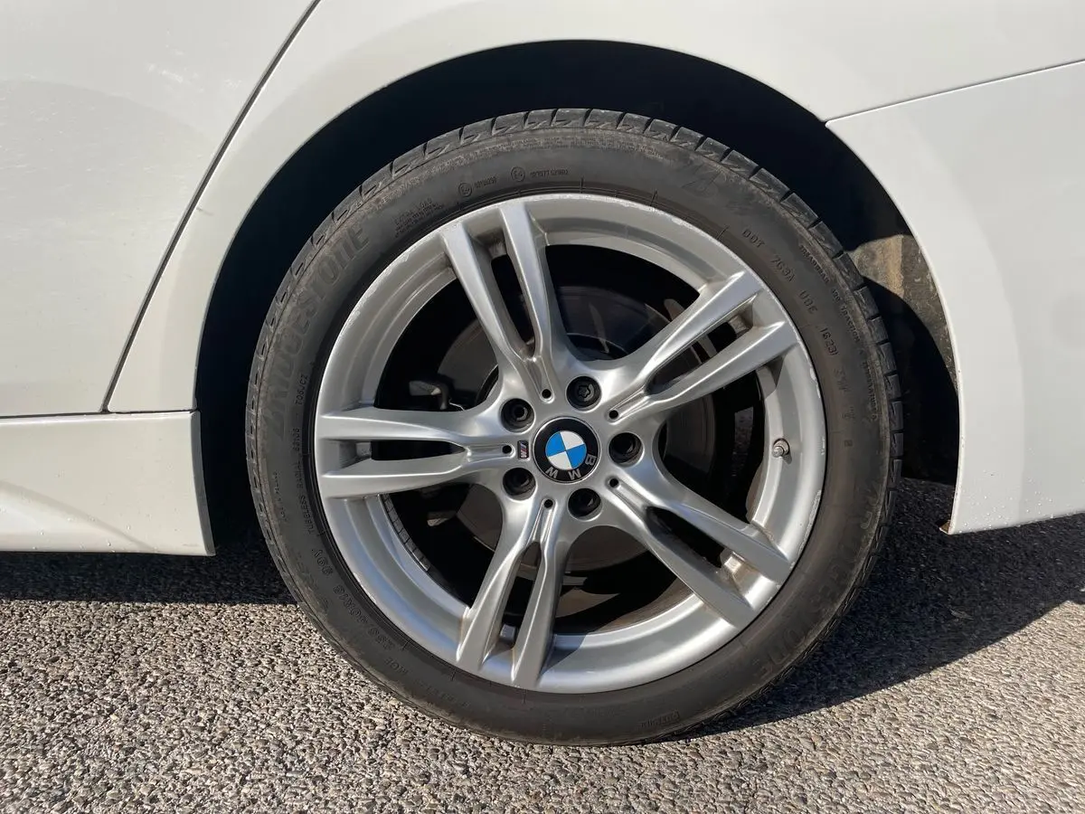 Gros plan sur la roue avant droite d'une BMW Série 3 Touring F31 blanche avec jante alliage M Sport visible.