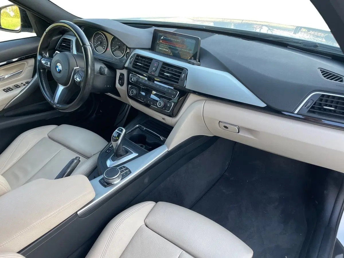 Vue intérieure côté conducteur de la BMW Série 3 Touring F31 330DA XDrive 2017 avec sellerie cuir beige et console centrale moderne.