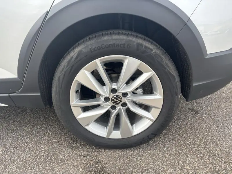 Gros plan sur la roue avant gauche avec jante alu argentée et logo Volkswagen sur un Taigo Reflet d'Argent métallisé.