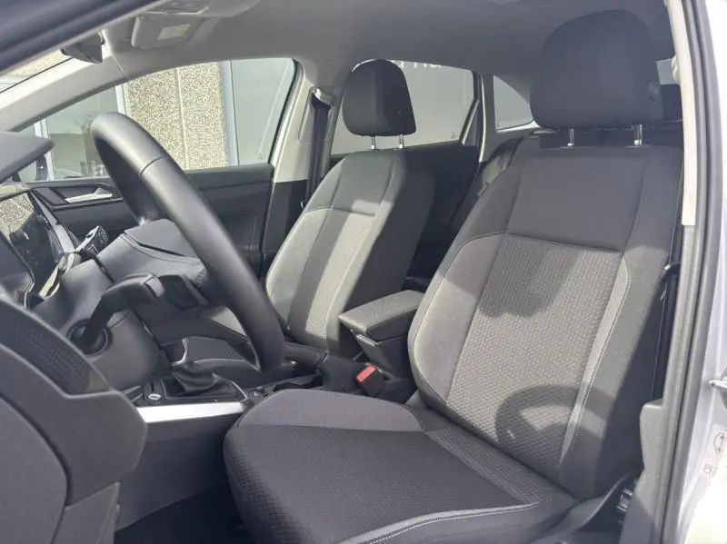 Intérieur avant du Volkswagen Taigo 2025 en Reflet d'Argent, sièges tissu noir ArtVelours et accoudoir central visible.