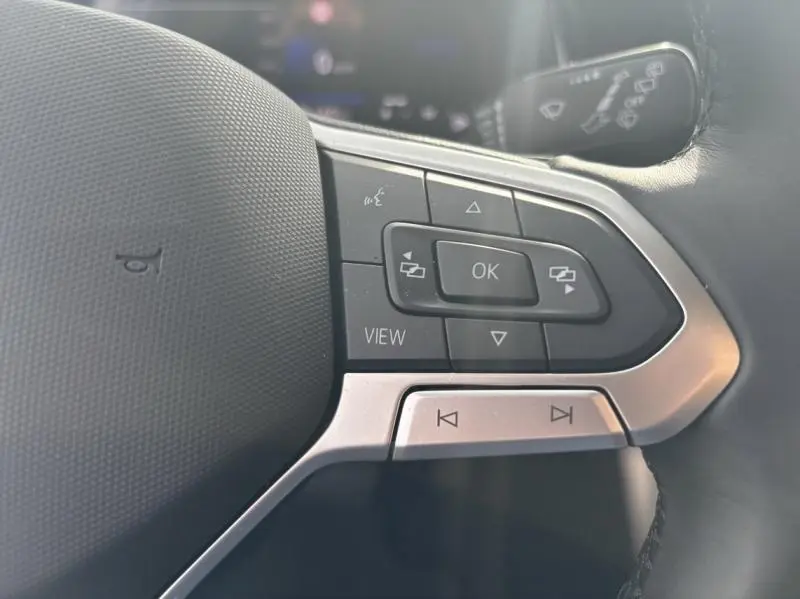 Gros plan sur les commandes multifonctions noires et argentées du volant cuir du Volkswagen Taigo 2025 en Reflet d'Argent métallisée.