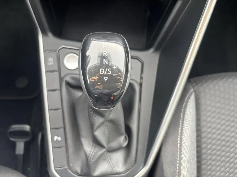 Le levier de vitesses automatique noir brillant du Volkswagen Taigo 2025 vu de dessus avec console et siège tissu gris.
