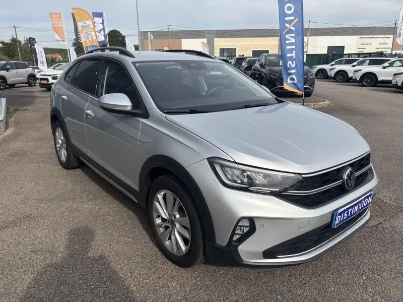 Volkswagen Taigo 2025 Reflet d'Argent métallisée en 3/4 avant droit avec barres de toit et jantes alu visibles.