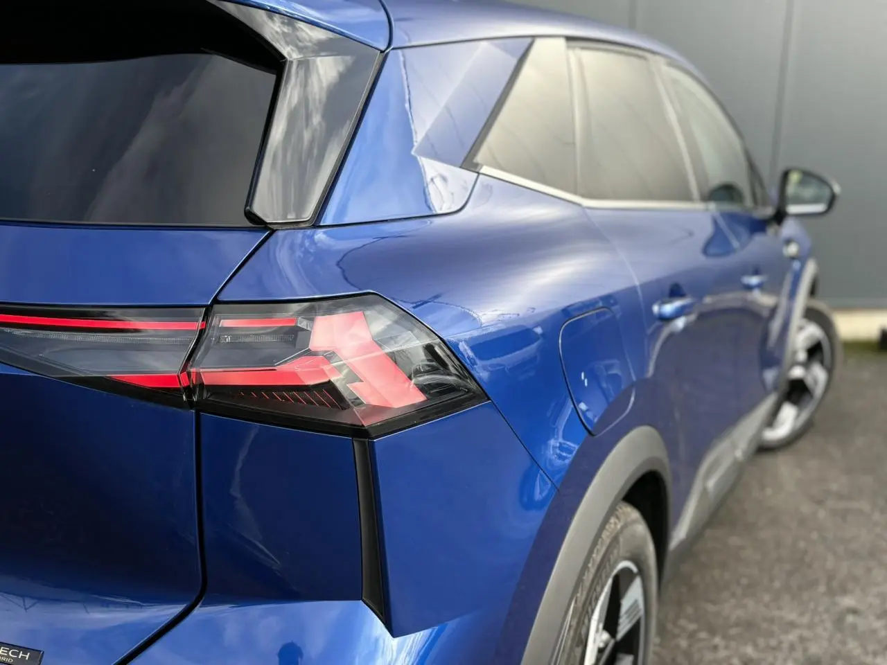 Vue 3/4 arrière droite du Renault SYMBIOZ bleu Iron, mettant en valeur les feux arrière LED et la ligne fluide du hayon.