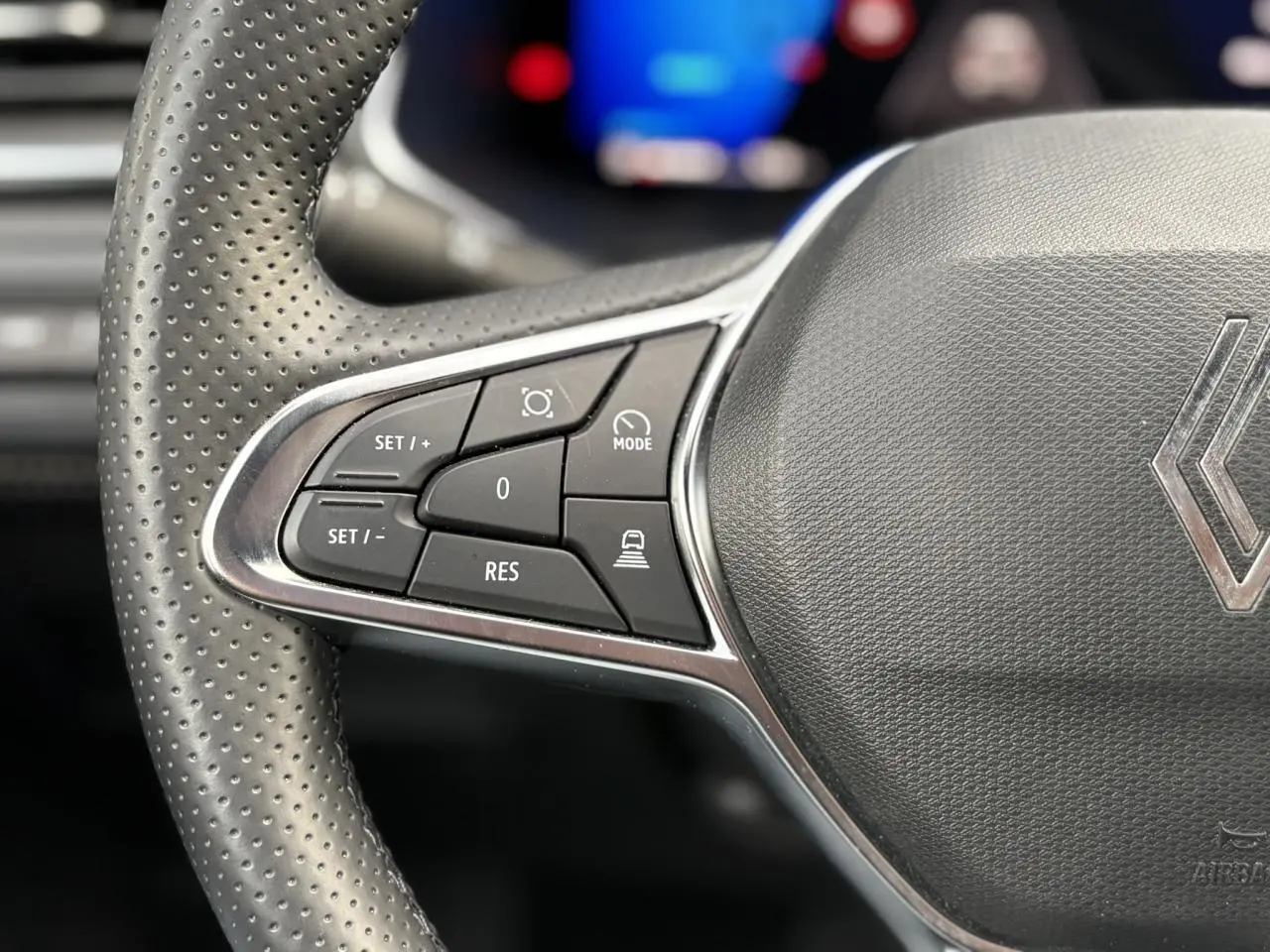 Gros plan sur le côté gauche du volant perforé gris avec commandes de régulateur sur Renault Symbioz 2025.