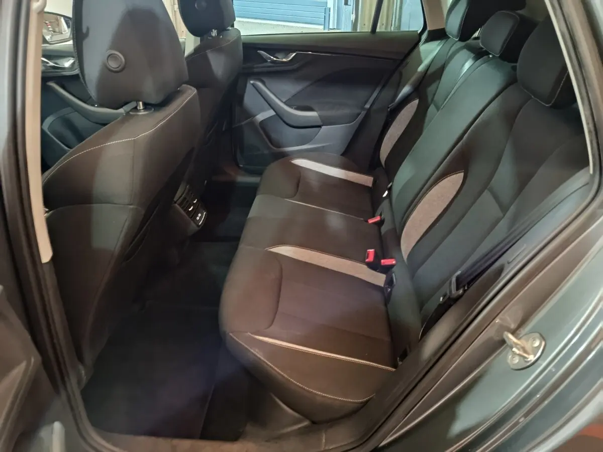 Vue intérieure côté gauche des sièges arrière noirs et gris du Skoda Kamiq gris clair 2024, avec portières ouvertes.